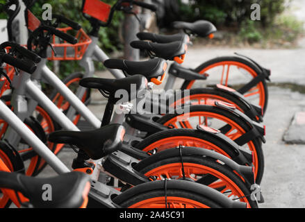 Transport rue hybride orange louer des bicyclettes avec mode de paiement électronique pour voyager autour de la ville sont en ligne sur réseau de location parking Banque D'Images