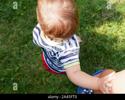 Enfant tient la main de maman. Vue de dessus. fond d'herbe verte. Banque D'Images