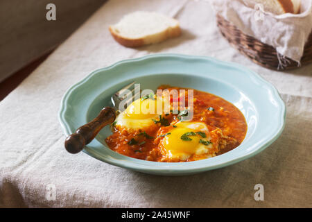 Shakshuka avec du pain sur une table en bois. Plat traditionnel du Moyen-Orient. Fait maison. Focus sélectif. Banque D'Images