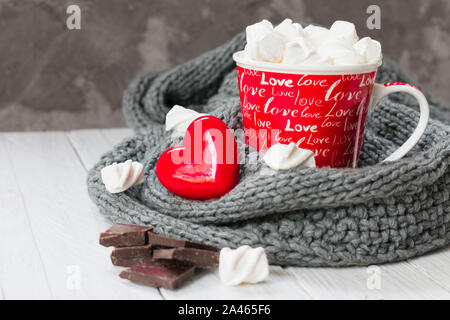 La Saint Valentin, une tasse de chocolat chaud avec une agréable boisson guimauve foulard gris, et un cœur rouge. Banque D'Images