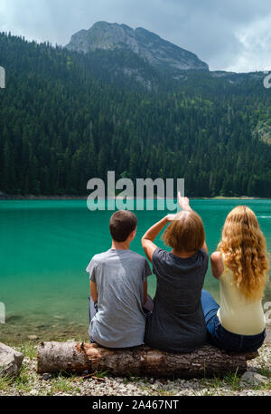 Famille, de la mère avec garçon et fille, reste sur tree log sur le lac Noir (Crno jezero), shore paysage estival. Municipalité de Zabljak, au Monténégro. Banque D'Images