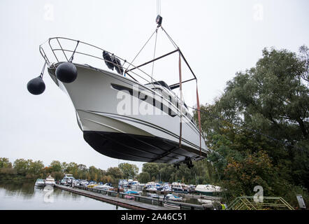 Hambourg, Allemagne. 12 octobre, 2019. Un yacht à moteur est soulevé hors de l'eau par une grue dans un yacht club. Crédit : Daniel Bockwoldt/dpa/Alamy Live News Banque D'Images