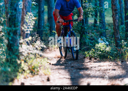 Plus l'excès de l'homme monte un VTT à travers les bois à l'aide d'un effort extrême. Banque D'Images