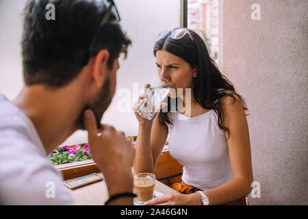 Jeune couple assis dans un café, boire un café le matin et avoir une conversation agréable Banque D'Images