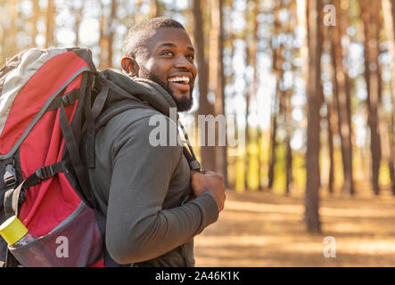 African man wearing backpack debout sur piste forestière Banque D'Images