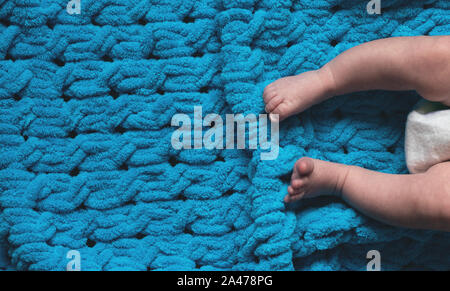 Les jambes d'un bébé nouveau-né sur un couvre-lit bleu doux avec copie espace . Banque D'Images