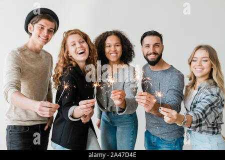 Rangée de jeunes enthousiastes friends holding feux de Bengale mousseux à l'avant de l'appareil photo Banque D'Images