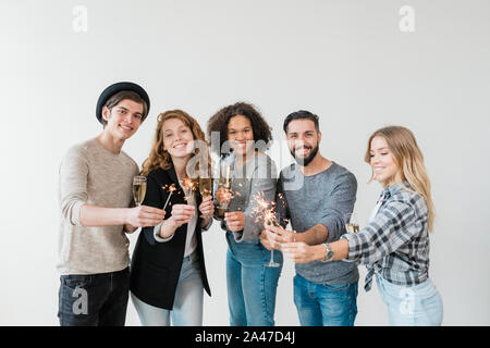 Cheerful friends toasting with flutes de champagne et feux de Bengale holding Banque D'Images
