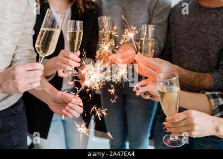 Groupe d'amis holding flutes de champagne et de brûler des feux de Bengale Banque D'Images