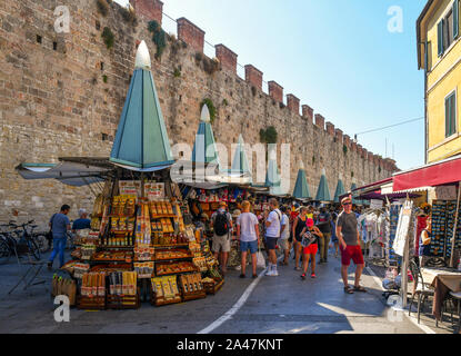 Vue sur la rue de la célèbre destination touristique et les gens d'acheter à des marchands de souvenirs et les murs de la vieille ville en une journée ensoleillée, Pise, Toscane, Italie Banque D'Images