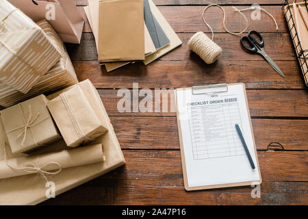 Liste de papier, stylo, boîtes emballées, fils, ciseaux et pile de blocs-notes Banque D'Images
