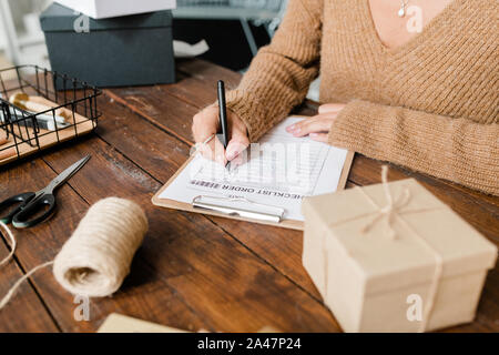 Client pull femme en mettant les tiques en face de marchandises commandées dans la liste de contrôle Banque D'Images