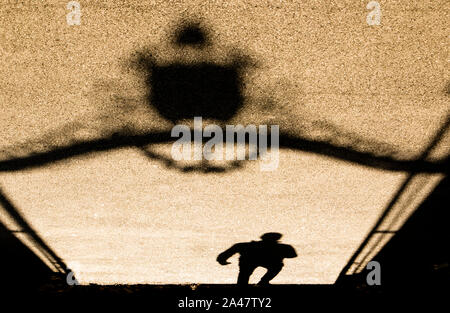 Ombres floues silhouette d'un homme passant par une énorme porte en métal vintage sépia Noir et blanc Banque D'Images