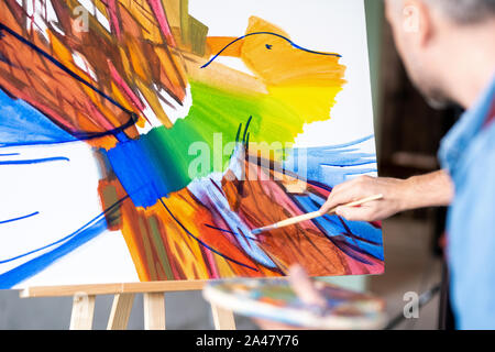 Partie de la peinture abstraite sur la feuille de papier et de main de l'artiste avec paintbrush Banque D'Images