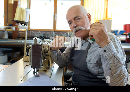 Mechanic repairing senior en usine de machines à coudre industrielles Banque D'Images