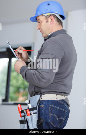 Foreman writing on clipboard en intérieur Banque D'Images