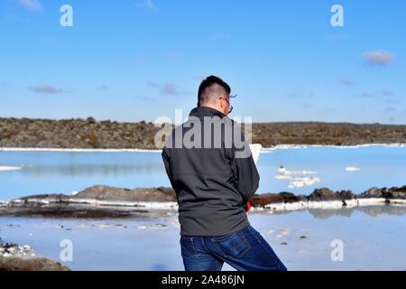 Svartsengi, Islande. Un guide touristique consulte un livre alors que sur les rochers entourant le Lagon Bleu L'une des principales attractions touristiques. Banque D'Images