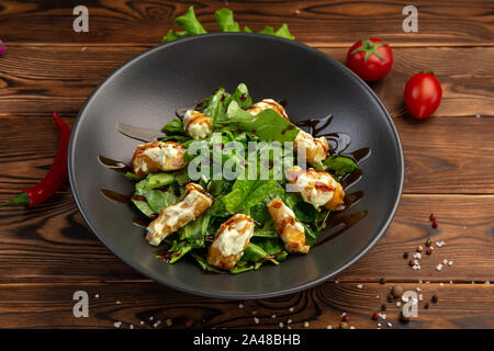 Wasabi ebi crevettes géantes en pâte avec épinards frais et laiteux-épicé sauce wasabi dans une plaque noire sur un fond de bois Banque D'Images