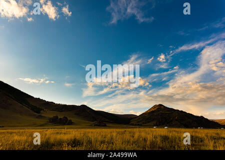 Le soleil se couche en Mongolie , Sunset Paysage photographie dans la steppe mongole à Arhangai-Aimag. Ciel bleu avec nuages blancs et steppe jaune Banque D'Images