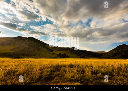 Le soleil se couche en Mongolie , Sunset Paysage photographie dans la steppe mongole à Arhangai-Aimag. Ciel bleu avec nuages blancs et steppe jaune Banque D'Images