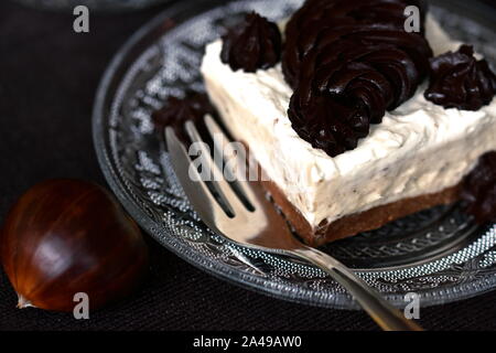 Tranche de gâteau à la crème de châtaigne servi sur assiette à dessert en verre transparent. Saison Automne dessert keto Banque D'Images