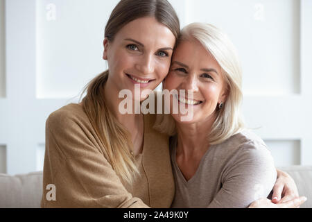 Belle mère et de sa fille adulte hugging looking at camera Banque D'Images