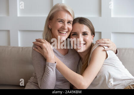 Heureuse mère âgée et sa fille adulte embrassant la main à l'intérieur Banque D'Images