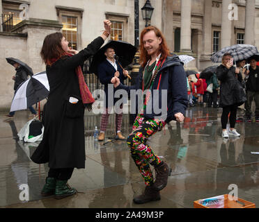 Londres, Royaume-Uni. 12 octobre 2019. Les manifestants ont vu danser sous la pluie à la musique d'un busseur londonien sur Trafalgar Square à Londres. Credit: Joe Kuis / Alamy News Banque D'Images