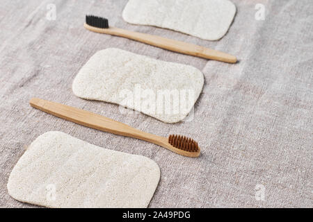 Brosses à dents en bois naturel et washclothers sur fond gris, vue du dessus Banque D'Images