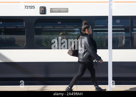 Londres, Royaume-Uni - 15 septembre 2019 : une femme vêtue de noir toutes les promenades sur une plate-forme à côté d'un train de la ligne sud-est. Banque D'Images