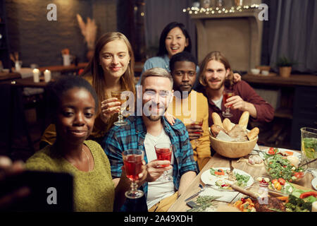 Multi-ethnic group of friends prendre photo selfies via smartphone tout en appréciant le dîner de travail à la maison, copy space Banque D'Images