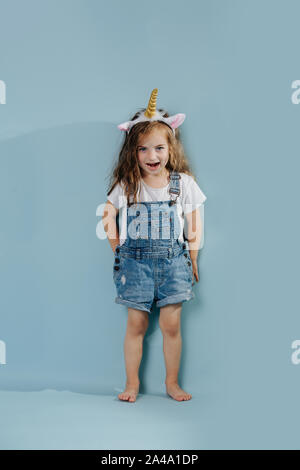 Playful girl wearing headband avec corne de licorne et les oreilles Banque D'Images