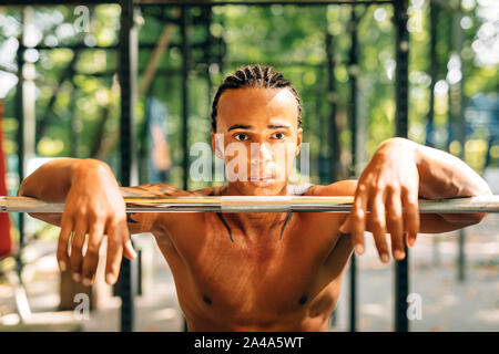 Portrait d'un jeune sportif en appui au cours d'exercices s'appuyant sur une barre de poids Banque D'Images