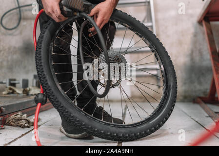 Mechanic repairing une roue de bicyclette à plat dans un petit atelier . Banque D'Images