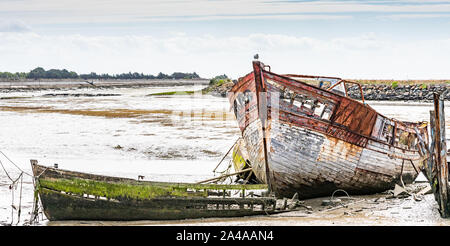 Le cimetière de bateaux de Noirmoutier. Un groupe d'épaves de vieux bateaux de pêche en bois sont empilés sur la boue. Banque D'Images