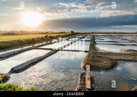 Les marais salants de l'île de Noirmoutier en France. Le soleil se lève sur des étangs, bassins et des tas de sel. Banque D'Images