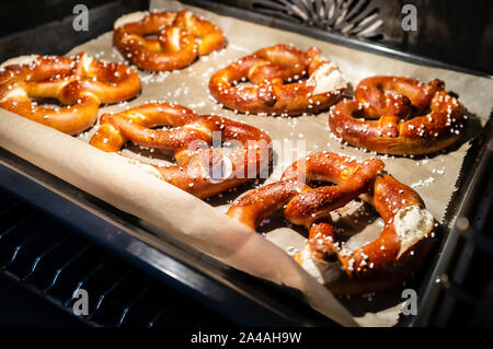 Appétissant, cuit au four, bretzels mous avec l'ajout de gros sel se trouvent sur le plateau dans le four. La nourriture traditionnelle. L'Oktoberfest. Close-up. Banque D'Images