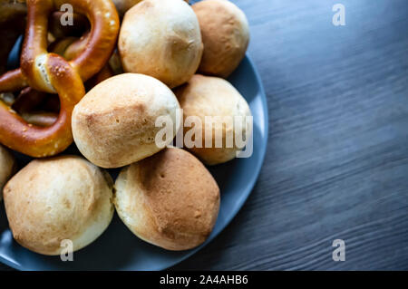 Appétissant, cuit au four, petits pains mous et les bretzels reposent dans une plaque, sur une texture en bois table. La nourriture traditionnelle. L'Oktoberfest. Close-up. Banque D'Images