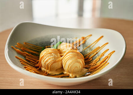 Trois boules de vanille habillé avec sauce au caramel, servi au restaurant sur la plaque. Banque D'Images