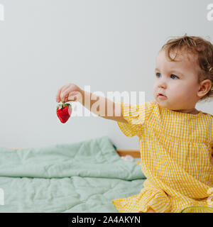 Belle jeune fille jouant avec la fraise. Gros plan carré Banque D'Images