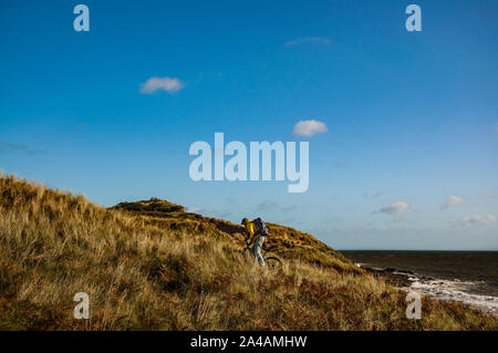 Randonnée à vélo en Irlande. Loisirs de cycliste avec sac à dos et vélo de montagne équitation en amont dans les dunes de sable. Banque D'Images