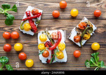 Collation santé et savoureux bruschettas avec légumes grillés et fromage sur la table en bois brun. Vue d'en haut. Banque D'Images