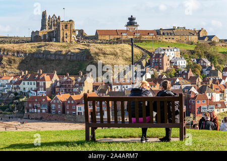 Deux femelles assis sur un banc en bois donnant sur les gens en utilisant les 199 marches de l'abbaye de Whitby et de l'église de Saint Mary Banque D'Images