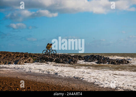 Randonnée à vélo en Irlande. Cycliste avec loisirs vtt et sac à dos en poussant son vélo en mer des rochers sur le bord de mer ondulée. Banque D'Images