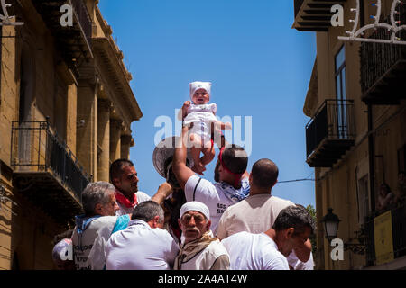 Pèlerinage religieux italien. Foule de gens portant la statue de saint de couleur en bas de la rue. Banque D'Images