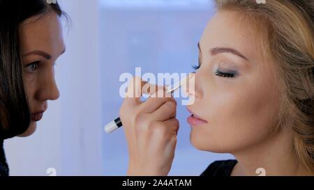 Maquilleuse professionnelle appliquant le maquillage sur visage de femme Banque D'Images