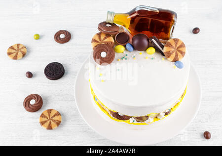 Drôle de gâteau avec une bouteille d'alcool, des bonbons et biscuits on wooden table Banque D'Images