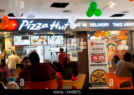 Foule de gens assis à l'extérieur d'un magasin de Pizza Hut en Inde Asie Banque D'Images