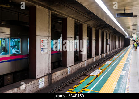 TOKYO, JAPON - 6 octobre 2018. Les hommes japonais sont assis dans le train à la station de métro et les gens attendent sur la plate-forme dans le métro de Tokyo. Banque D'Images