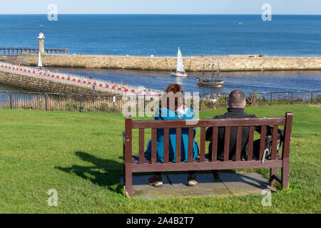 Un yacht et HMS Endeavour de l'expérience du capitaine Cook, tous deux quitter Whitby Harbour Vue du haut de la promenade de West Cliff Banque D'Images